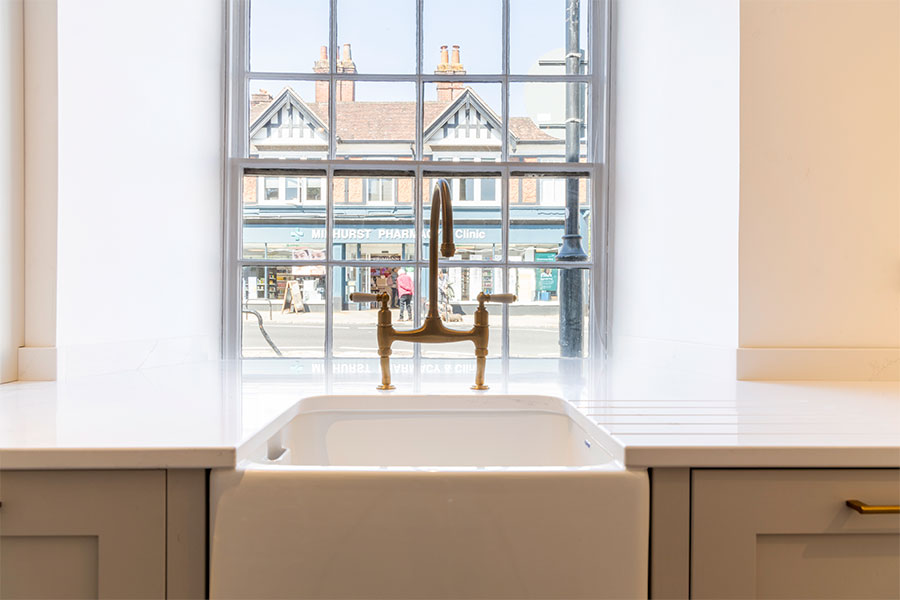 White stone kitchen worktop with Belfast sink and period brass taps on display in Midhurst at Sussex Stoneworks