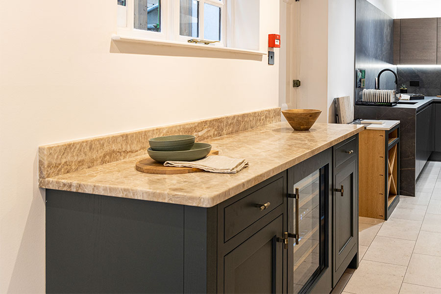 Dark blue in-frame kitchen in the Claremont Kitchens & Interiors showroom with custom made Taj Mahal Quartzite stone worktop made by Sussex Stoneworks