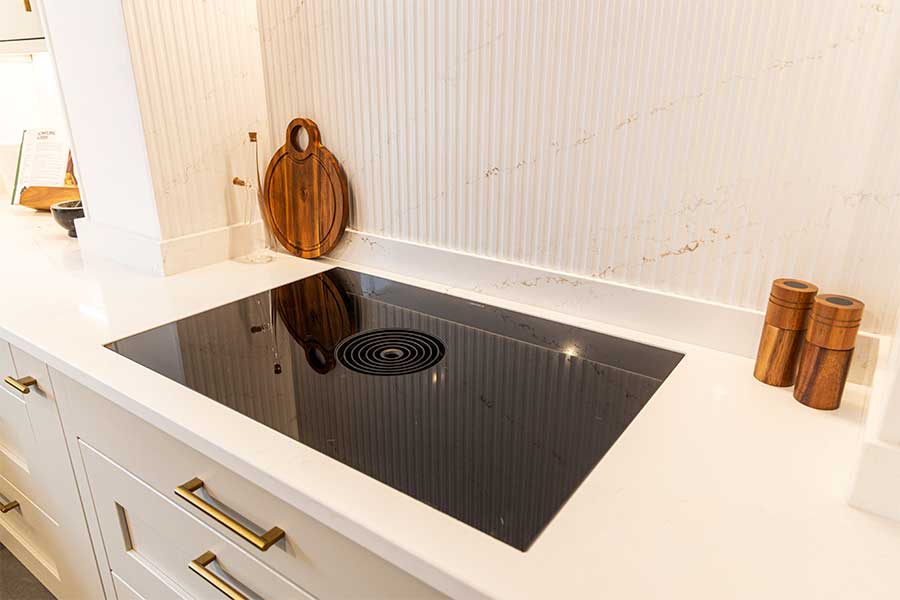 Sussex Stoneworks produced this Silestone quartz worktop with inset hob cut out, matching upstands and splashback with bespoke fluted detailing for the Claremont Kitchens Showroom in North Street, Midhurst.